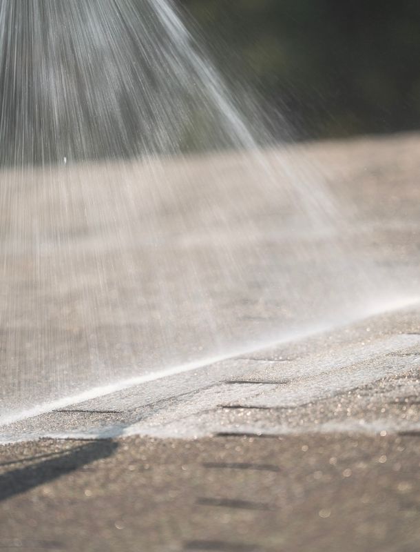 water spraying cleaning solution on the roof